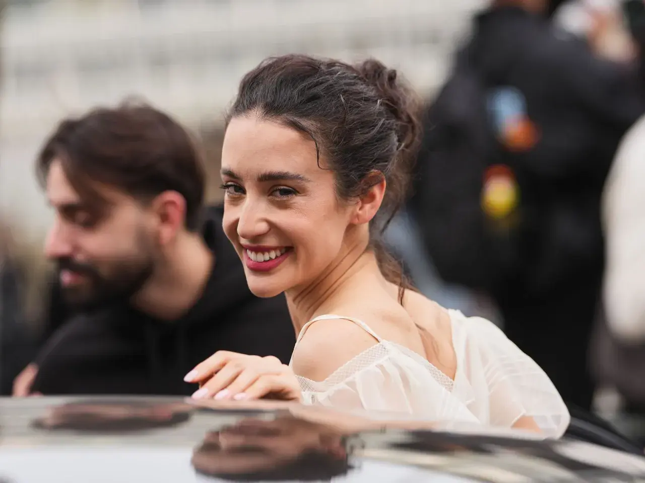 La belleza de Paula Badosa se refleja en su sonrisa radiante, con el cabello recogido y un vestido blanco delicado.