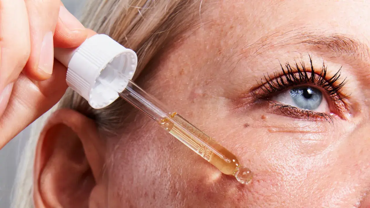 Una mano aplica un suero con un gotero sobre la piel. Descubre para qué sirve el retinol y cómo puede mejorar tu piel.