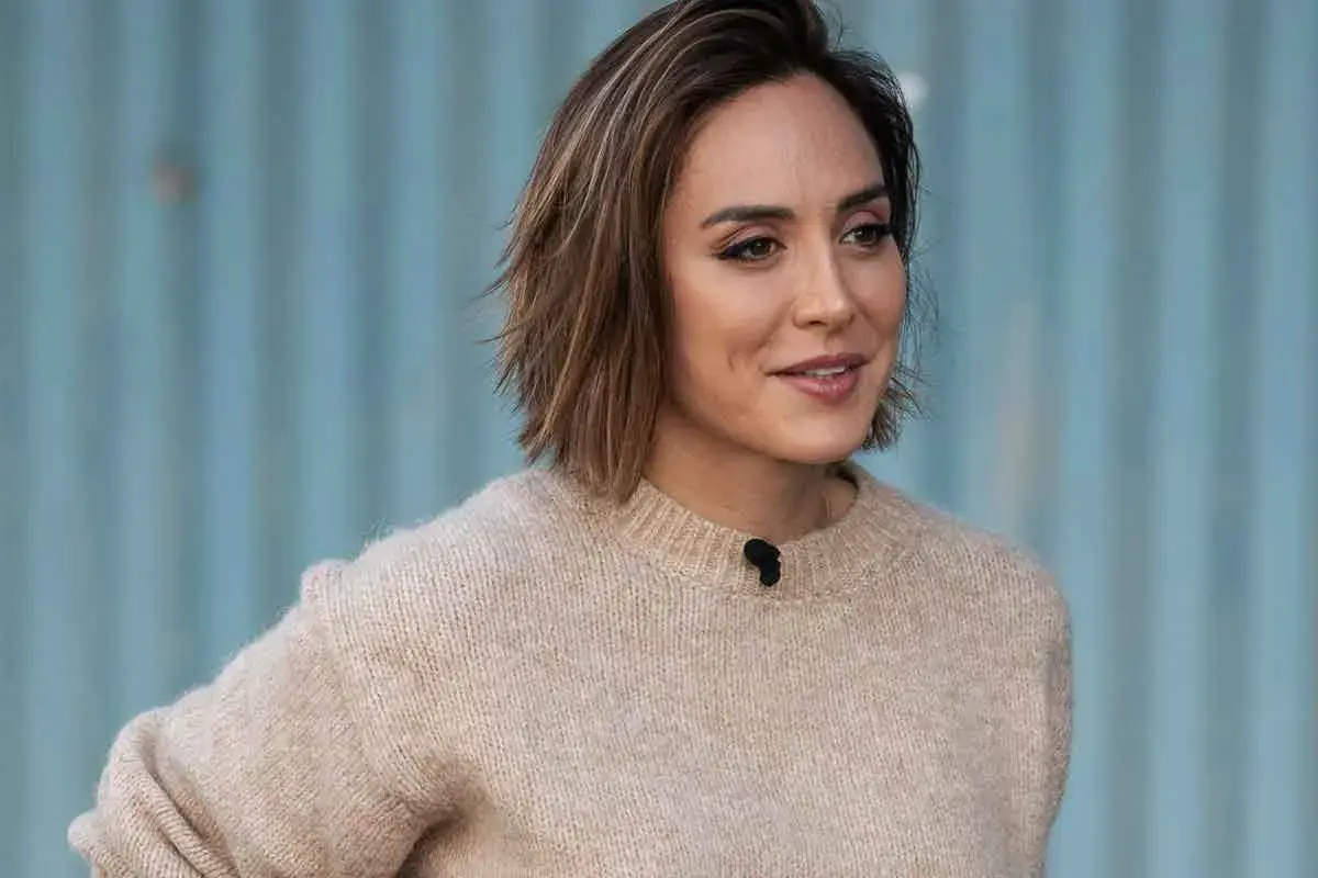 Mujer con un suéter beige y modernos cortes de pelo bob, con un fondo azul.