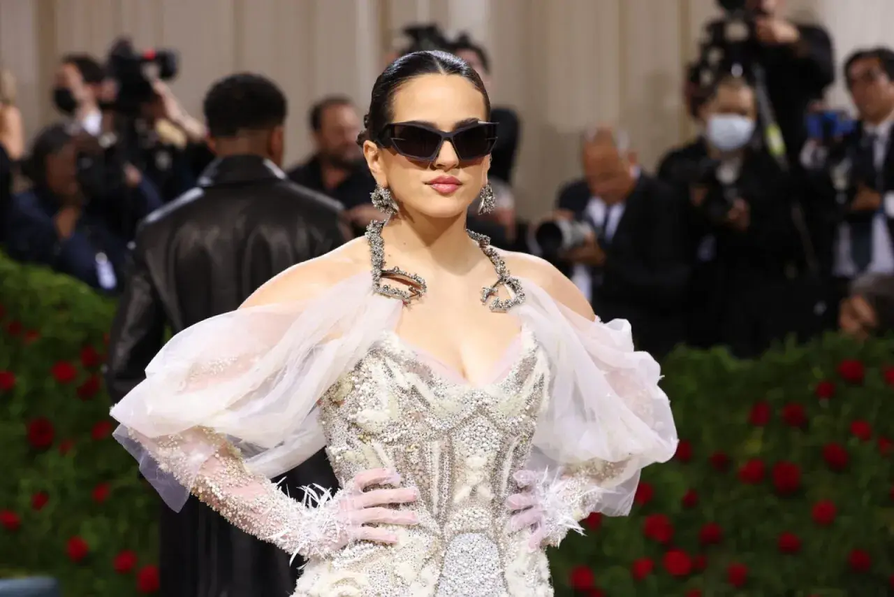 Rosalía deslumbrante en la Met Gala, con un vestido blanco adornado y gafas de sol audaces.