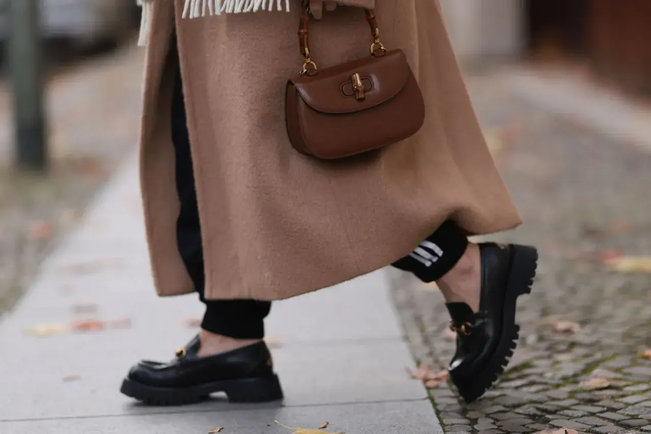 Abrigo camel, bolso marrón y mocasines negros. El marron y negro combinan a la perfección en este look otoñal.