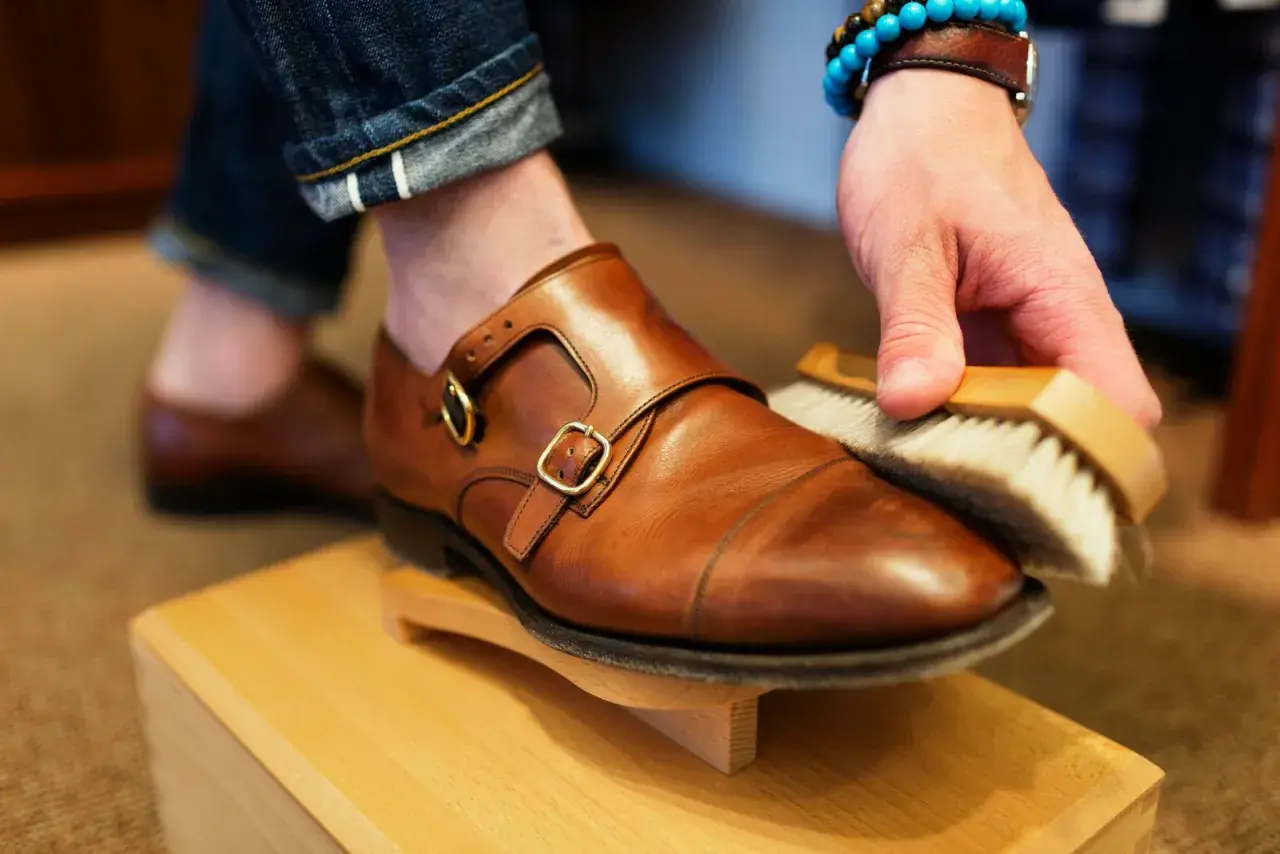 Hombre cepillando un zapato de piel marrón, parte de como limpiar zapatos de piel.