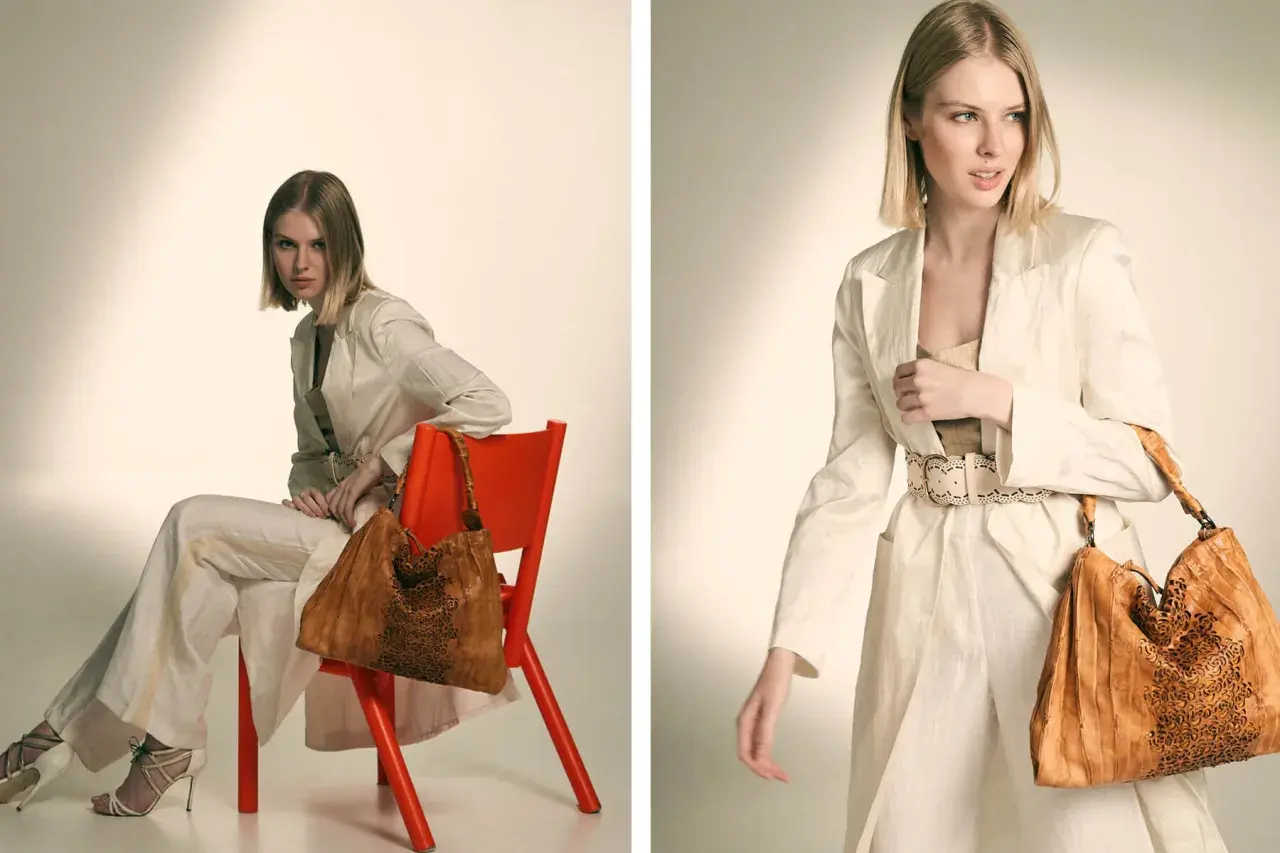 Modelo luce un traje beige y un bolso de cuero marrón con detalles calados.