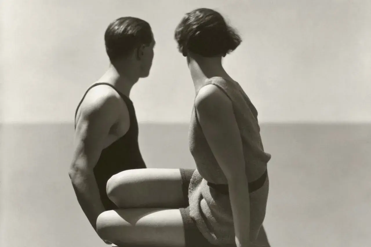 Pareja en trajes de baño, capturada por Patrick Demarchelier, mira hacia el mar.