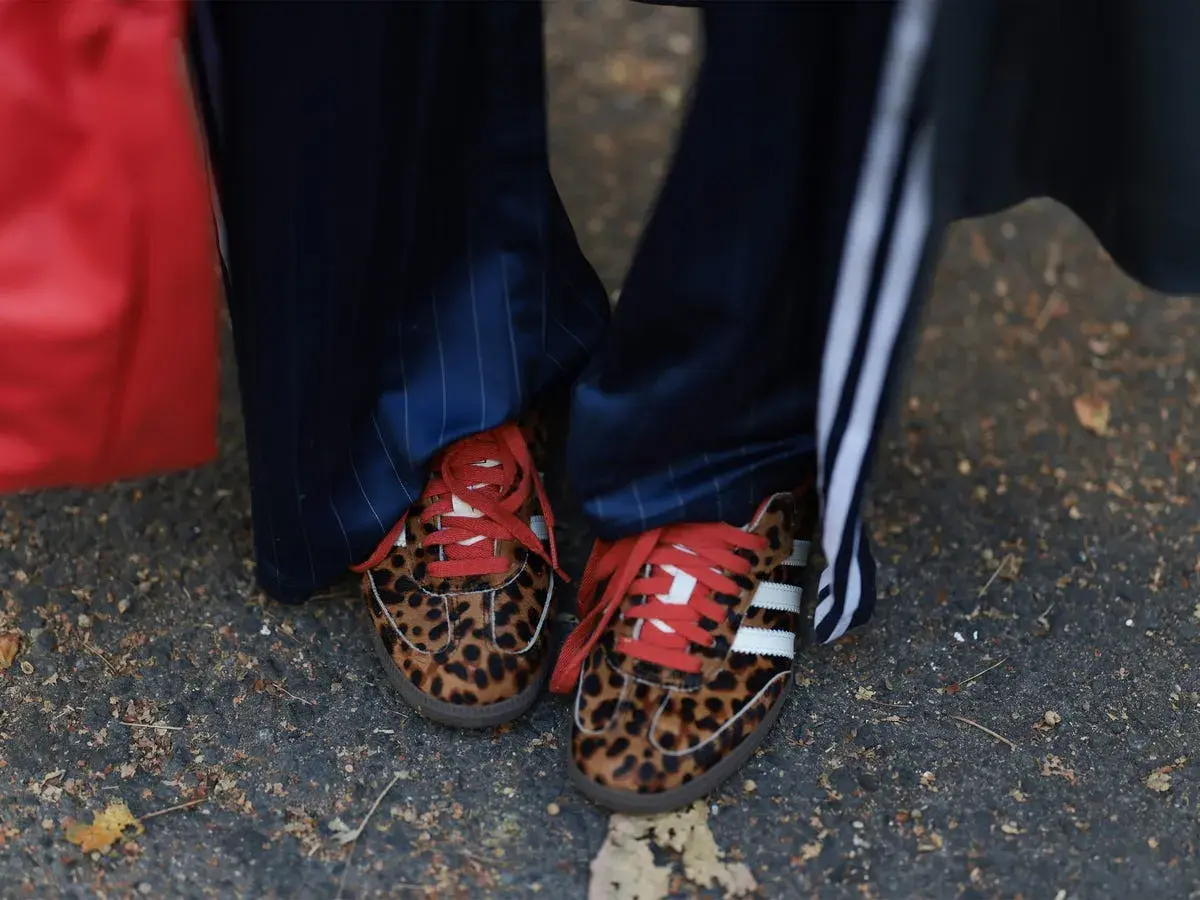 Zapatillas tendencia con estampado de leopardo y cordones rojos, combinadas con pantalones de raya diplomática.