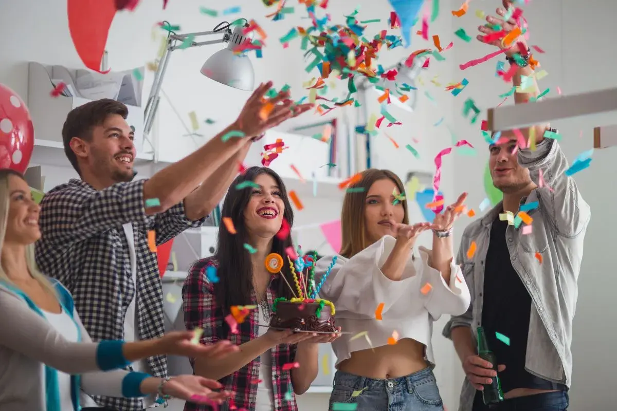 Jóvenes celebran un cumpleaños con confeti y pastel. ¡Una fiesta divertida para saber como vestir para un cumpleaños!