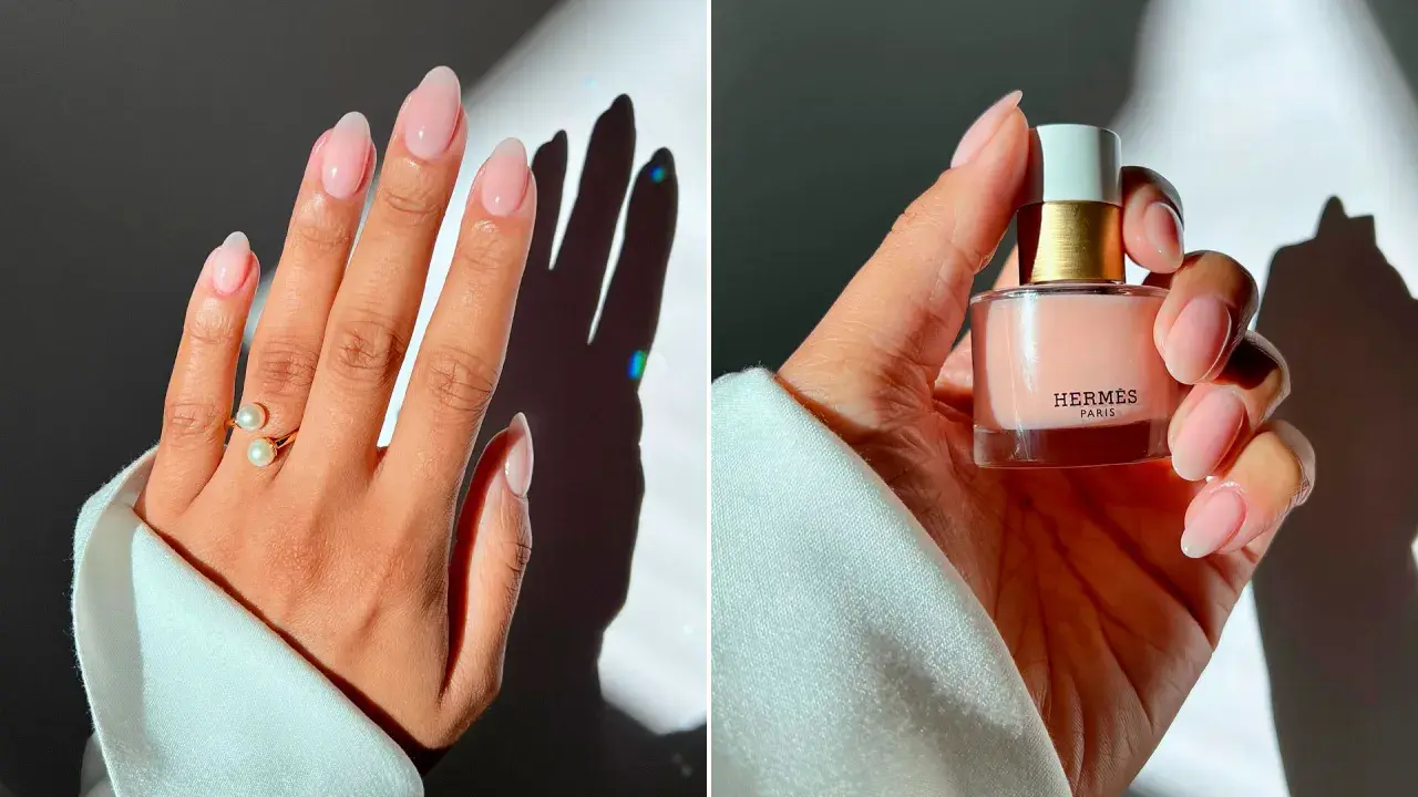 Manicura elegante con uñas nude, anillo de perlas y esmalte de uñas de Hermès.