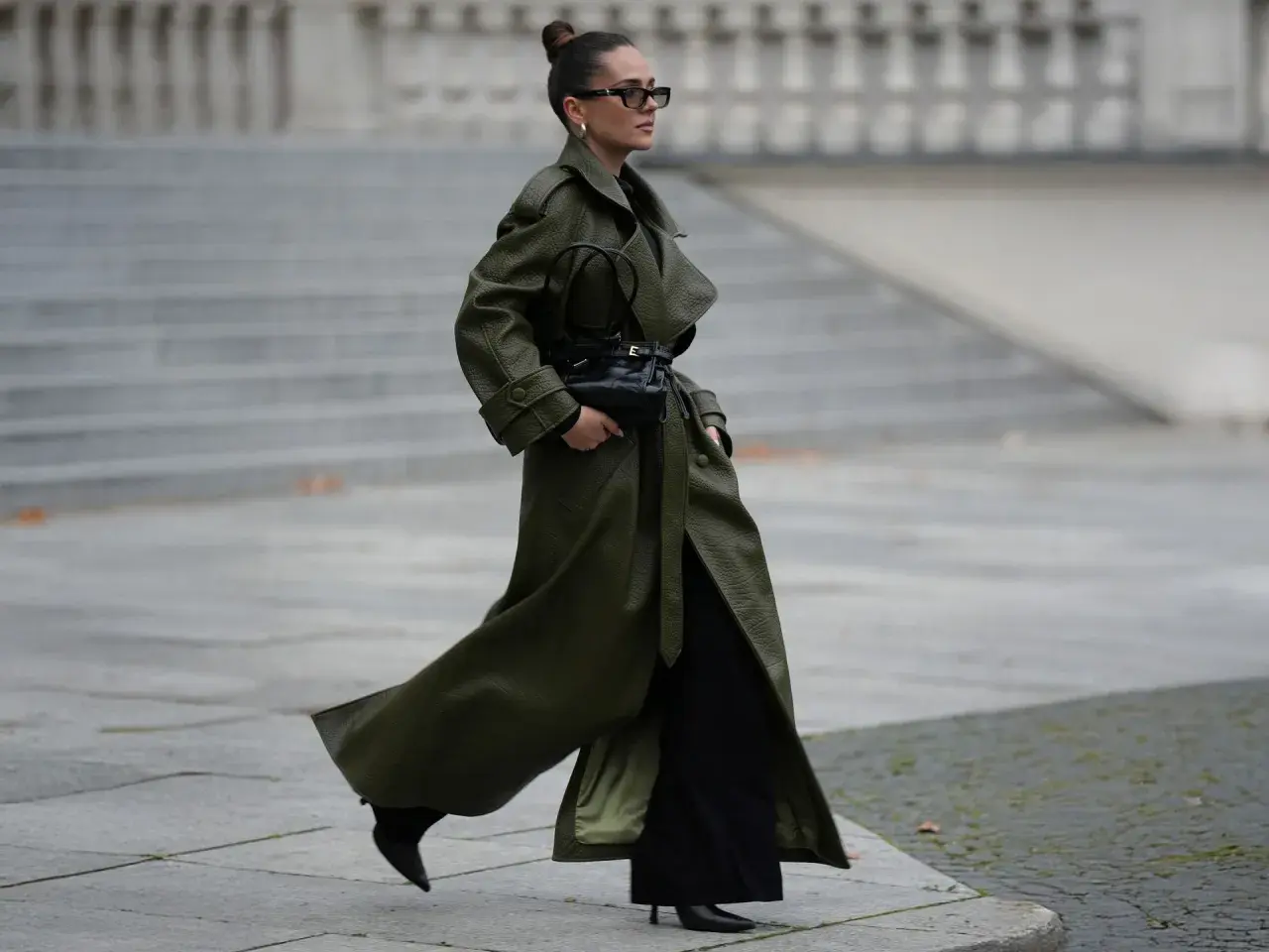 Mujer con abrigo verde olivo y bolso negro, demostrando colores que combinan con el negro.
