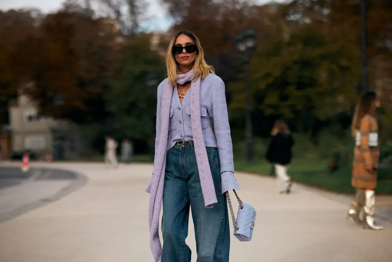 Mujer con look elegante con vaqueros, chaqueta lila, bufanda y bolso a juego.
