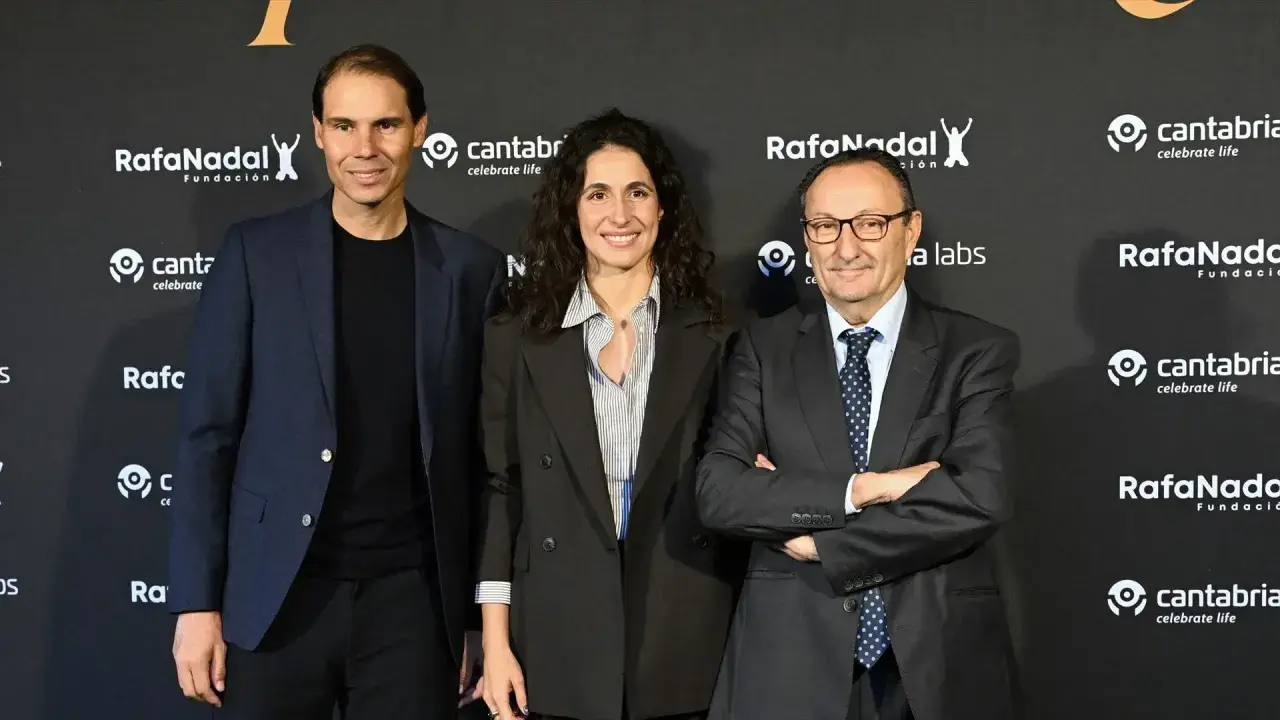 Rafael Nadal, Xisca Perelló y un hombre con traje posan ante un fondo con logos de la Fundación Rafa Nadal y Cantabria.