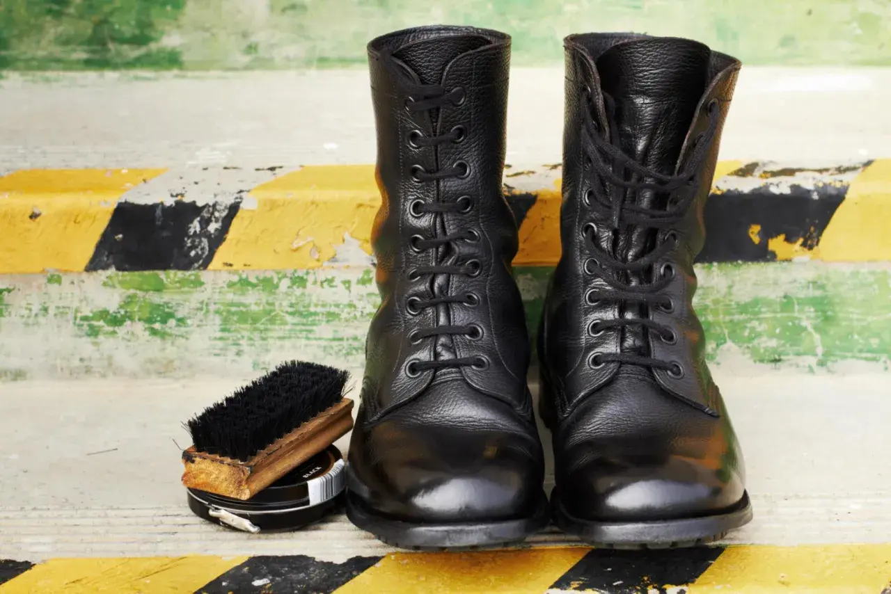 Botas militares negras, cepillo y betún. Aprende como limpiar botas militares para que luzcan impecables.