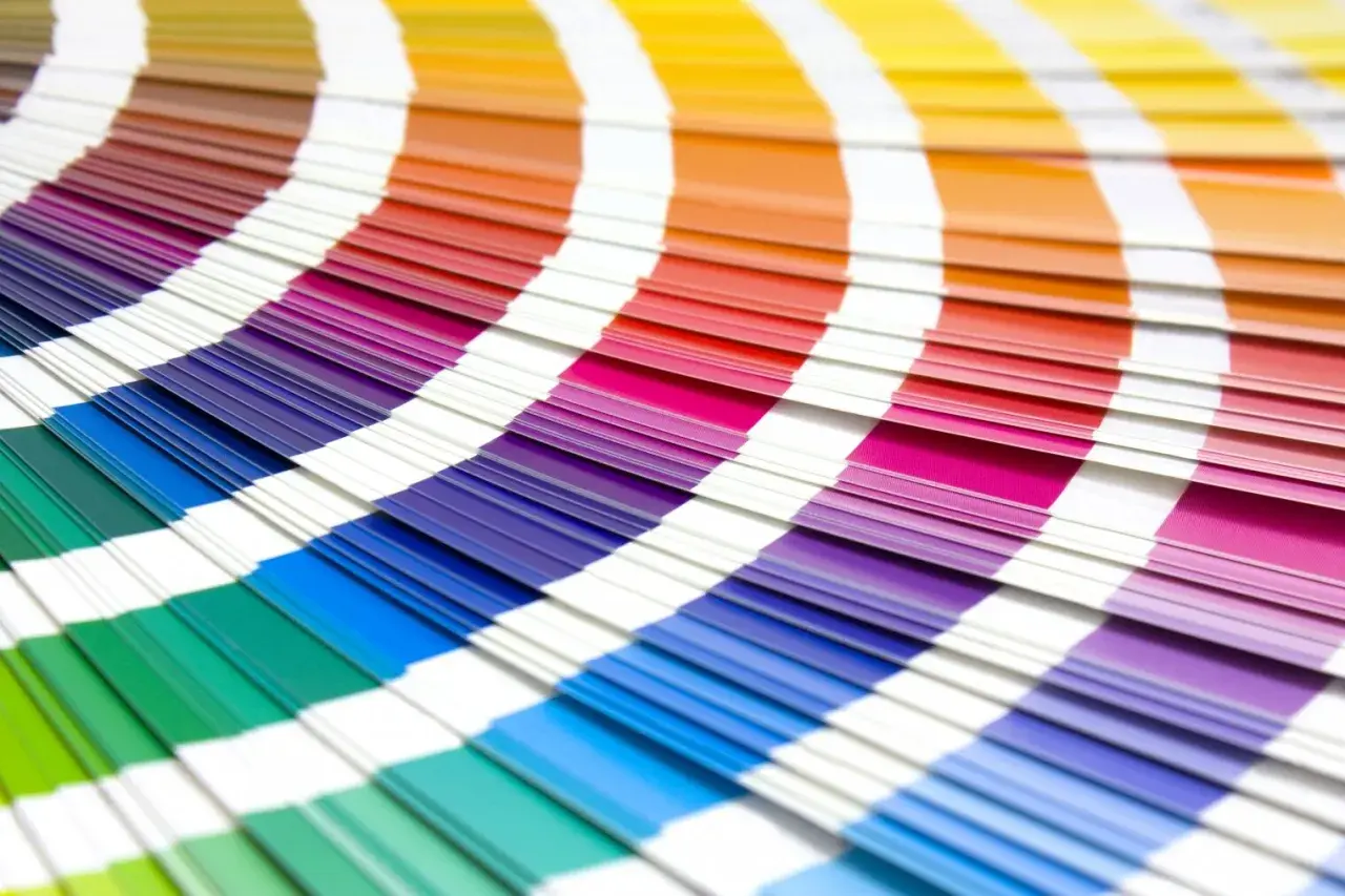 Abanico de muestras de color con tonos vibrantes, incluyendo el color burdeos y granate, que se despliegan en un arco iris de posibilidades.