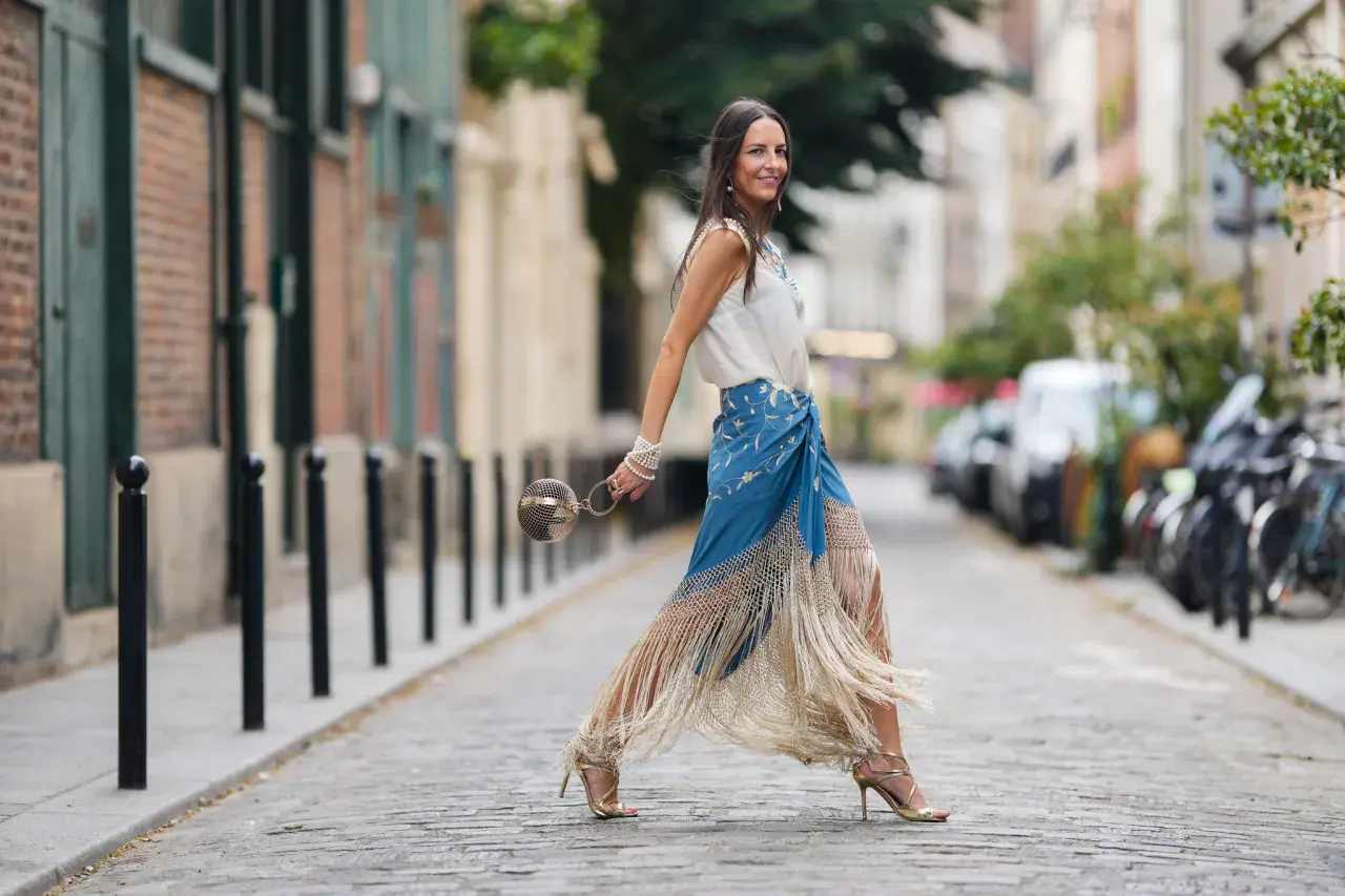 Mujer con falda larga azul con flecos y top blanco, perfecta ropa para ir a la feria de dia.