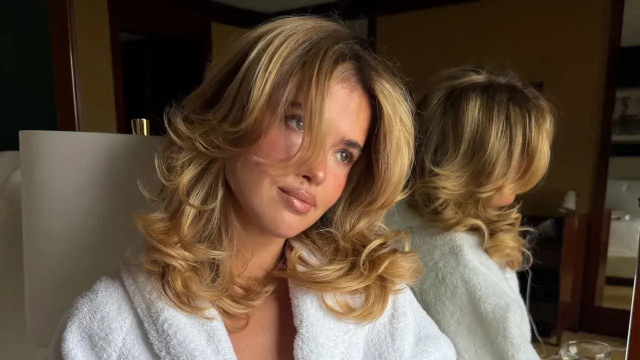 Chica con cabello rubio y rizado, luciendo unos cortes de pelo largo con capas voluminosas.