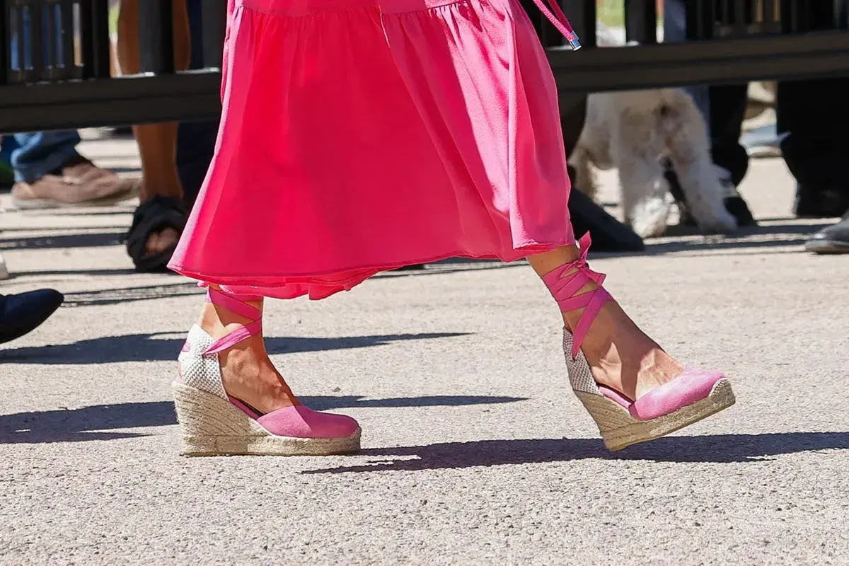 Pie de la Reina Letizia luciendo unas alpargatas de cuña rosas con cintas atadas al tobillo, combinadas con un vestido fucsia.