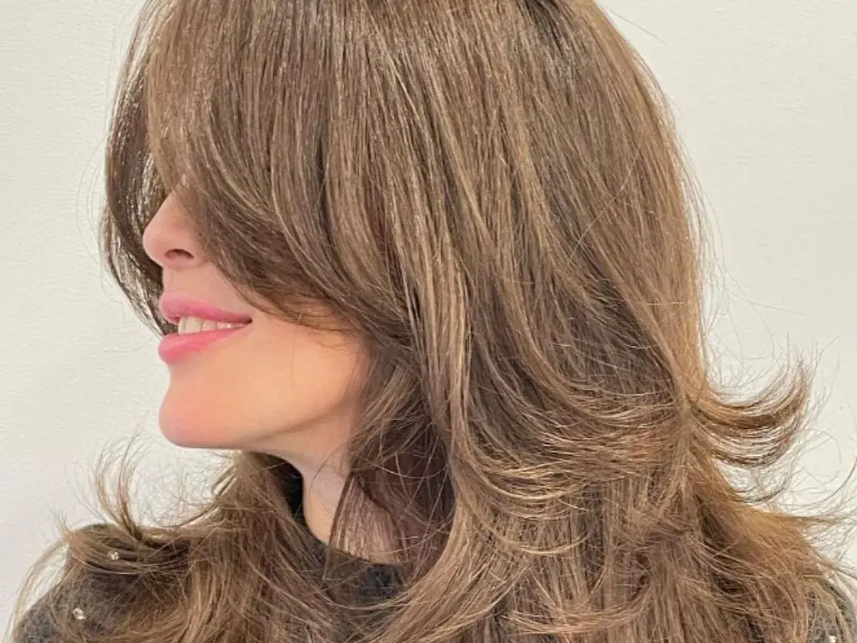 Cabello castaño con un corte mariposa, capas suaves que enmarcan el rostro y dan movimiento.