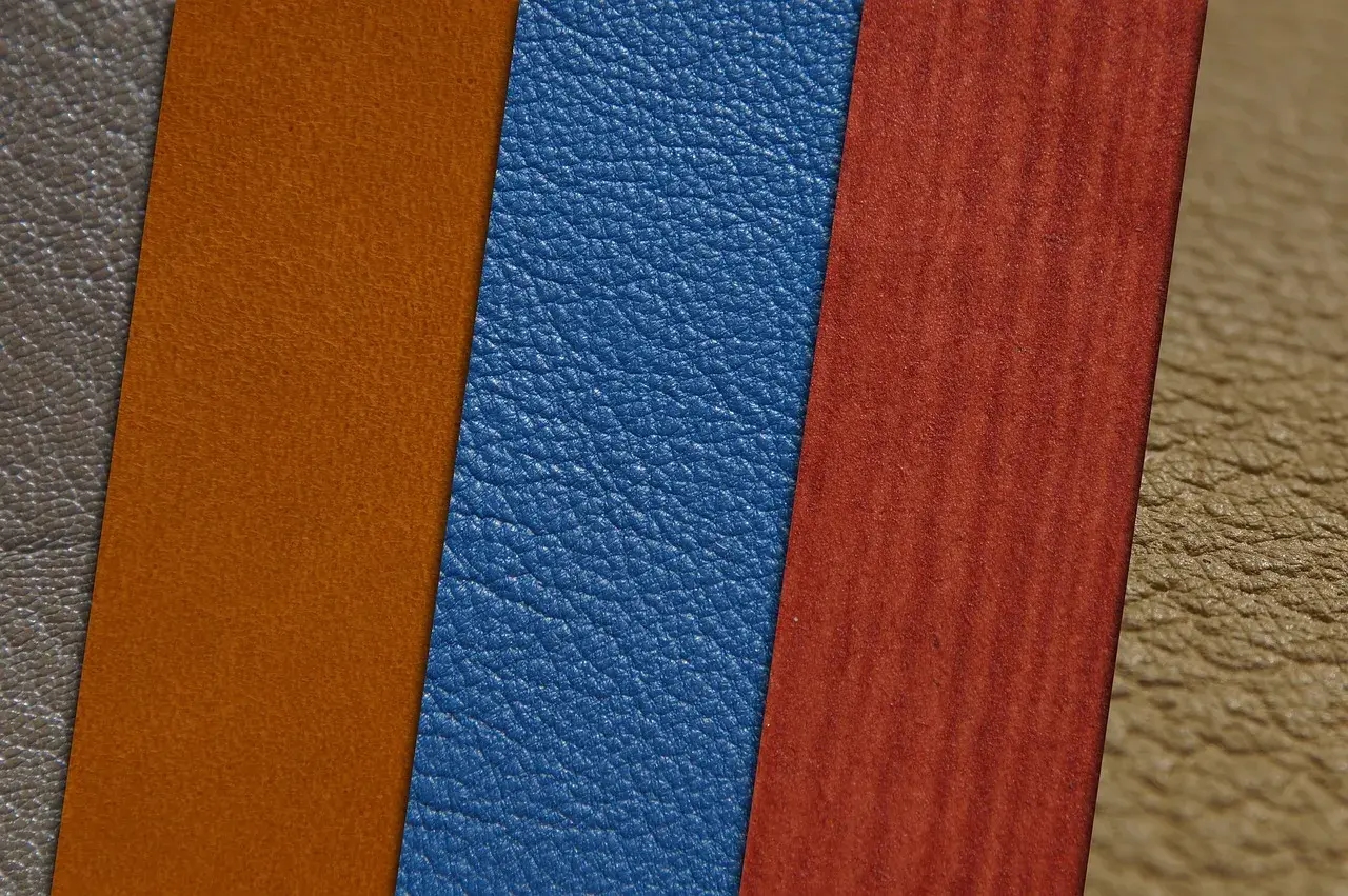 Muestras de materiales: cuero vegano azul, naranja y marrón, junto a un material rojo con vetas.