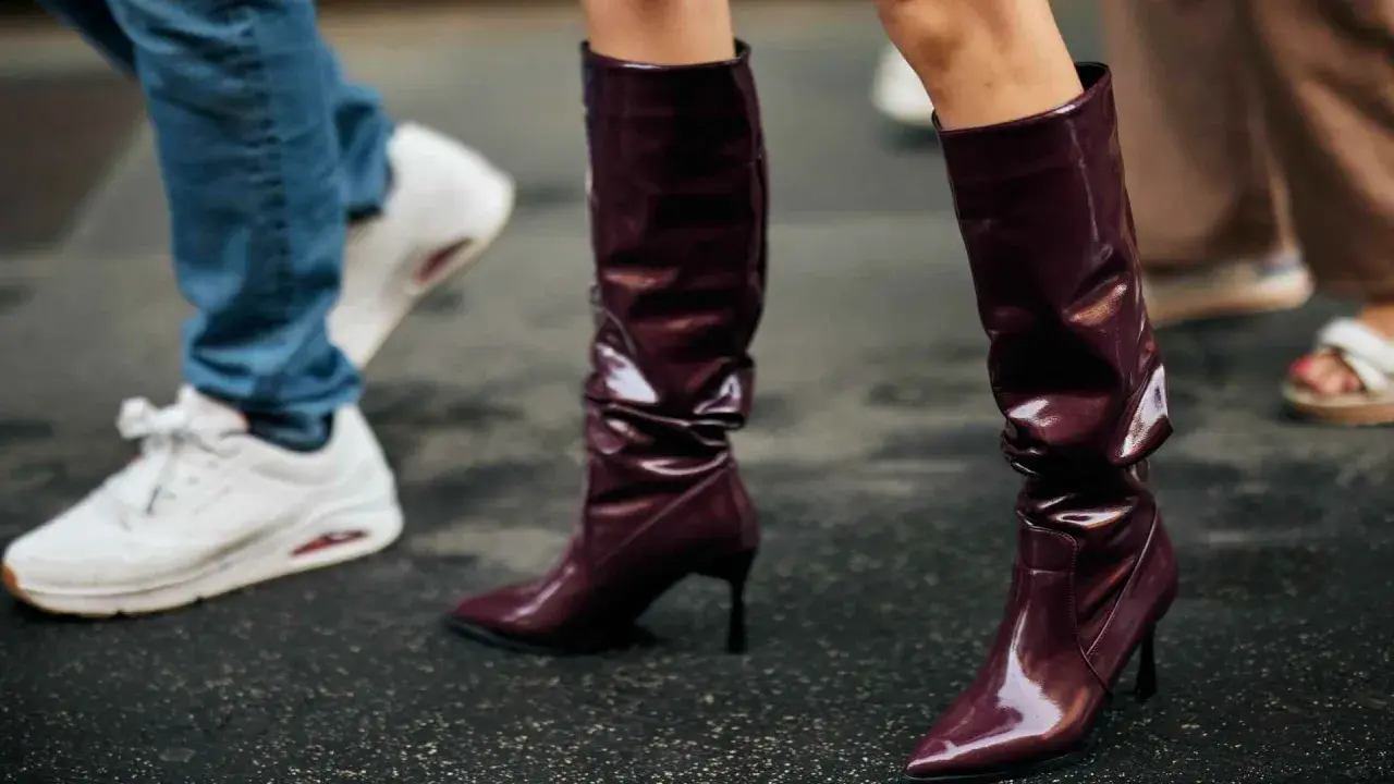 Se llevan las botas altas de charol burdeos, combinadas con vaqueros y zapatillas blancas.