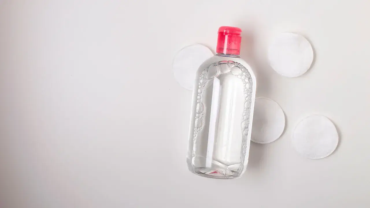 Botella de agua micelar con tapa rosa y discos de algodón. Ideal para limpiar ante y rostro.