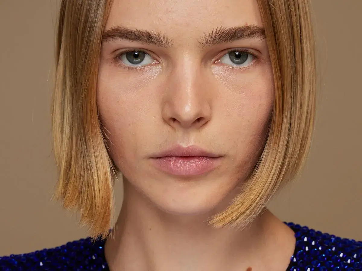 Primer plano de una mujer con un corte bob rubio y un vestido azul brillante.
