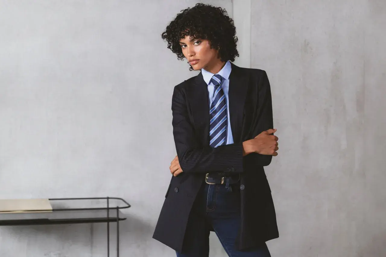 Persona andrógina con traje a rayas, camisa azul y corbata a juego.
