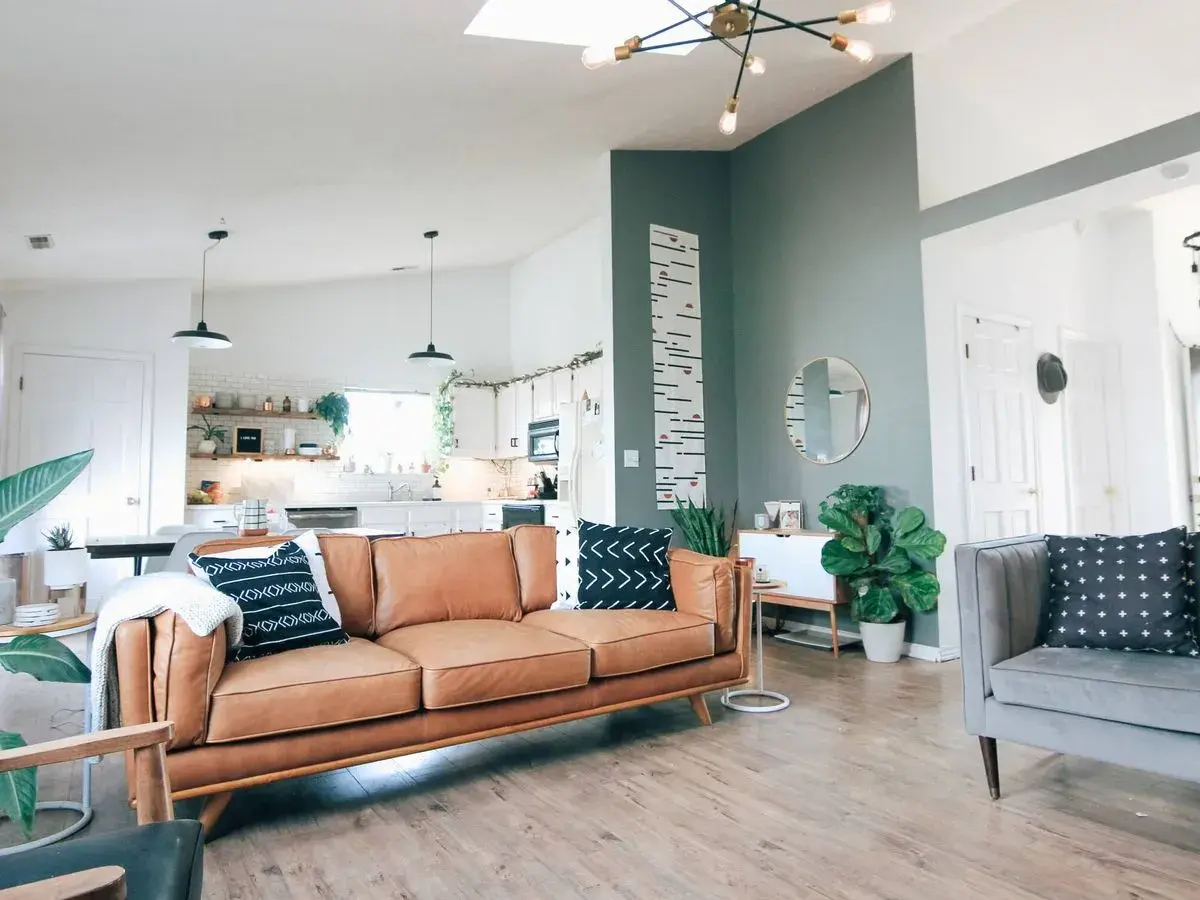 Sofá de cuero marrón y cojines con patrones en azul y verde combinan perfectamente en este salón moderno.