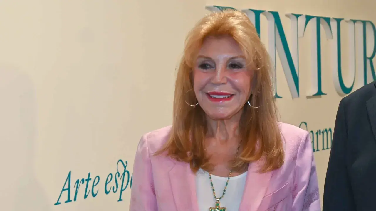 Tita Thyssen, con su icónico estilo, sonríe luciendo un blazer rosa y un collar llamativo.