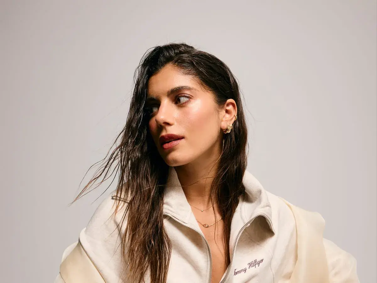 Sara Baceiredo, con su cabello largo y húmedo, luce un collar delicado y pendientes dorados.