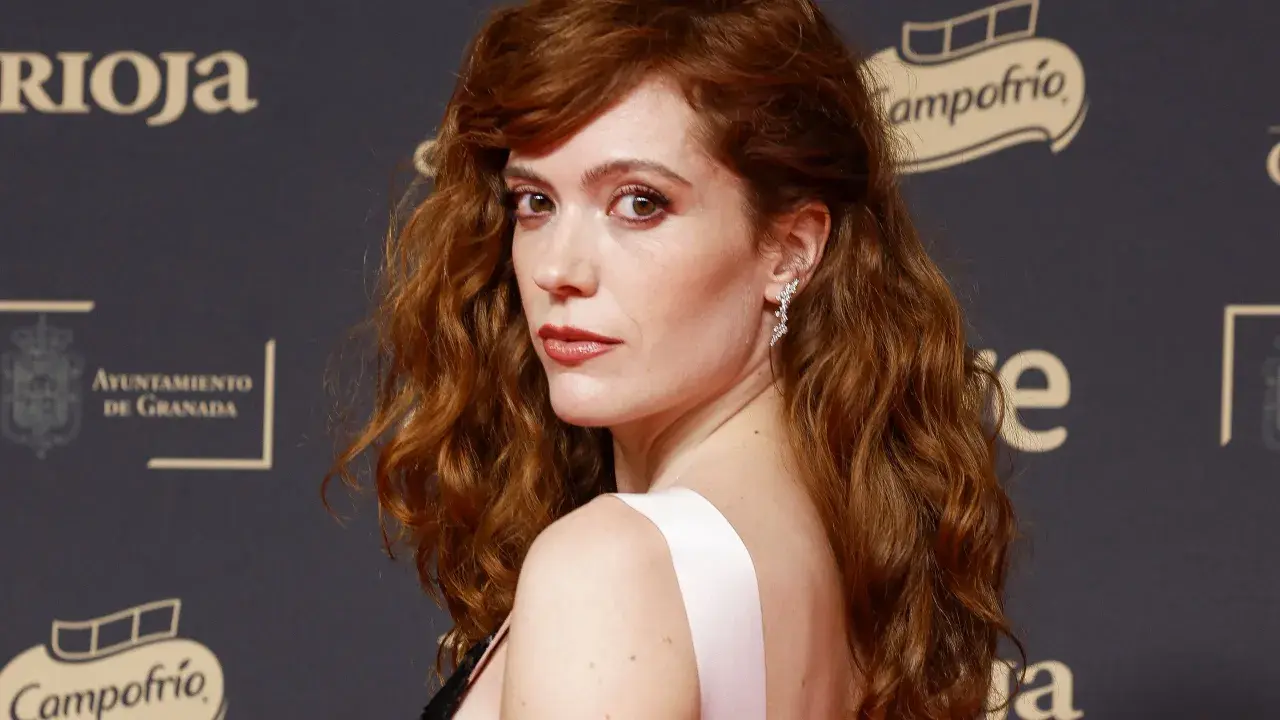 Itsaso Arana, con su cabello pelirrojo ondulado y un vestido rosa, posa con elegancia.
