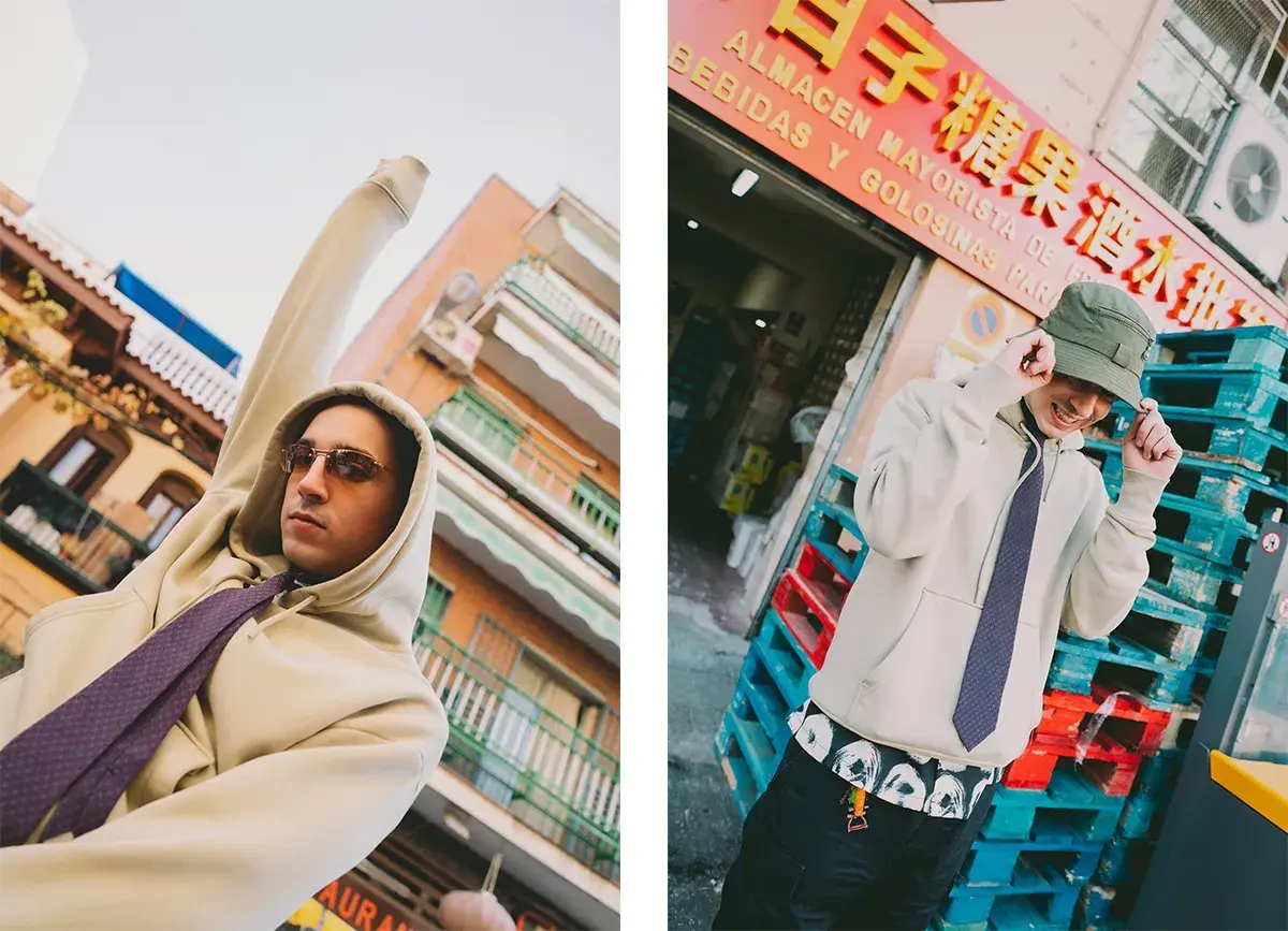Ralphie Choo, con sudadera y corbata, posa con estilo urbano frente a un almacén.
