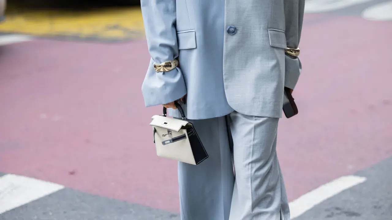 Traje gris con pantalones de pierna ancha (wide leg significado) y bolso blanco y negro.