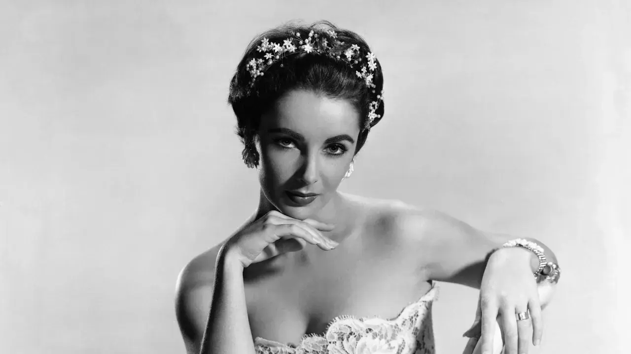 Elizabeth Taylor, con un tocado floral y un vestido de encaje, posa con elegancia.