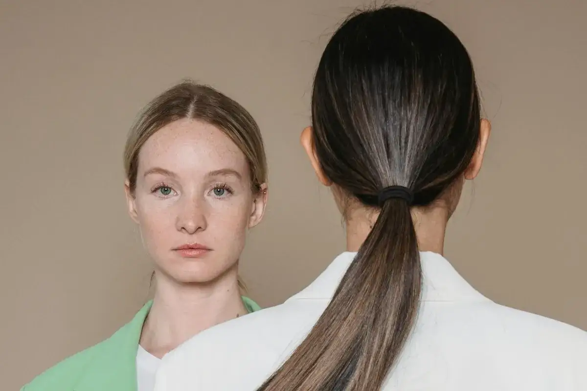 Dos mujeres, una de espaldas con coleta y otra de frente con pecas, comparten secretos sobre como cuidar el pelo.