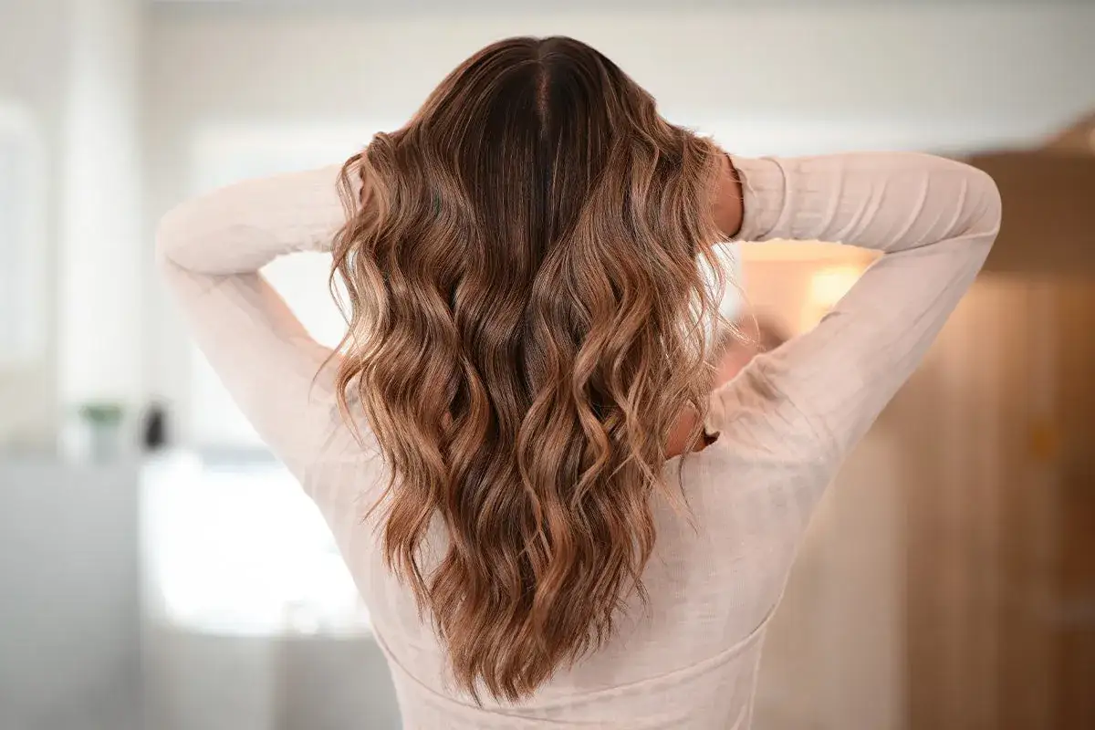Melena castaña con ondas surferas, un estilo desenfadado y natural que realza la textura del cabello.