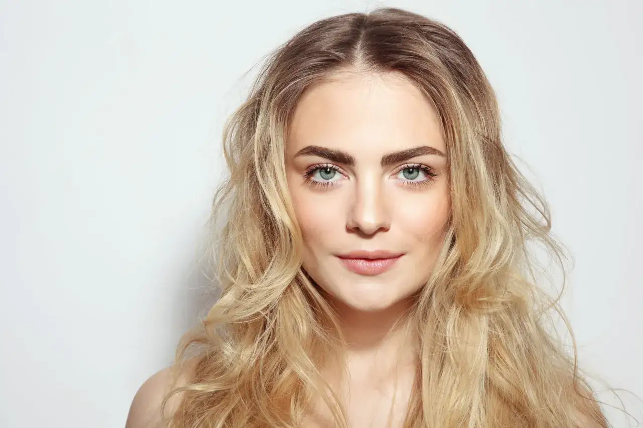 Mujer joven con cabello rubio y ojos verdes, ideal para un análisis de colorimetría.