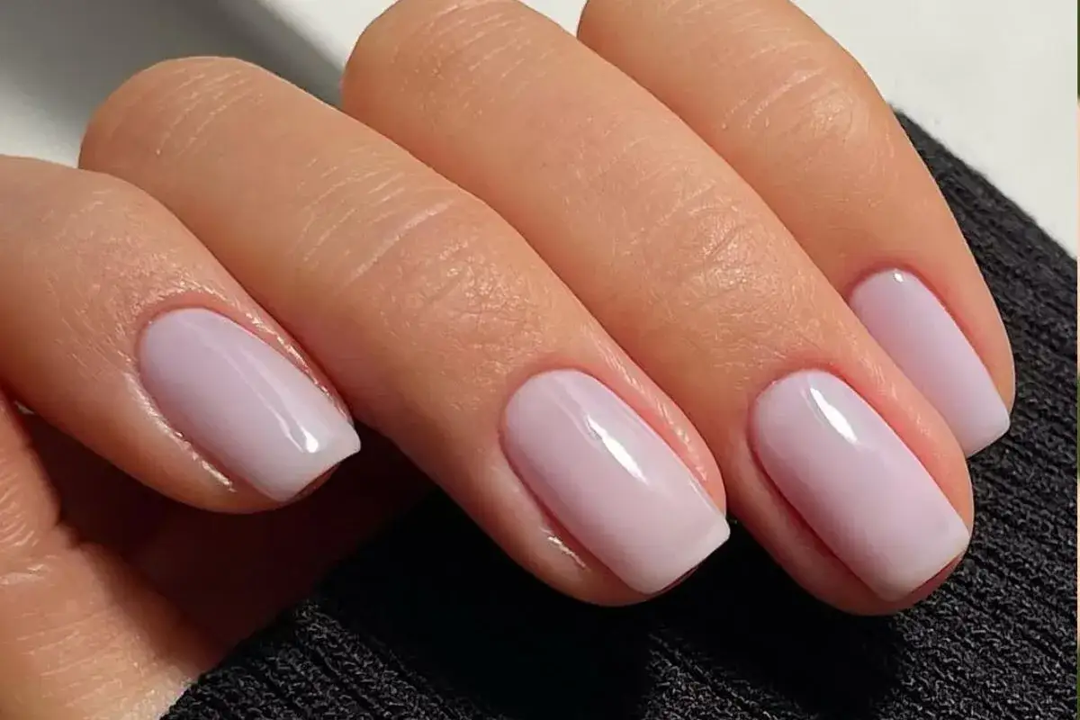 Manos con uñas color lavanda pálido, un tono que ilumina y da un toque juvenil.