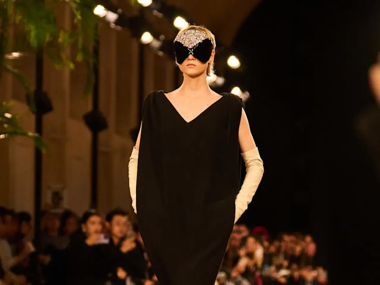 Modelo con máscara de pedrería y vestido negro en desfile de Pierpaolo Piccioli.