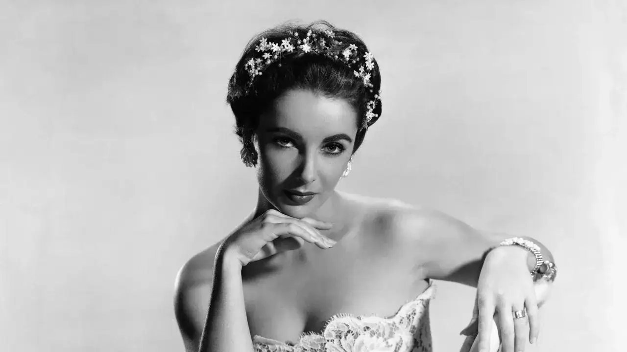 Elizabeth Taylor, con un tocado floral y un vestido de encaje, posa con elegancia.