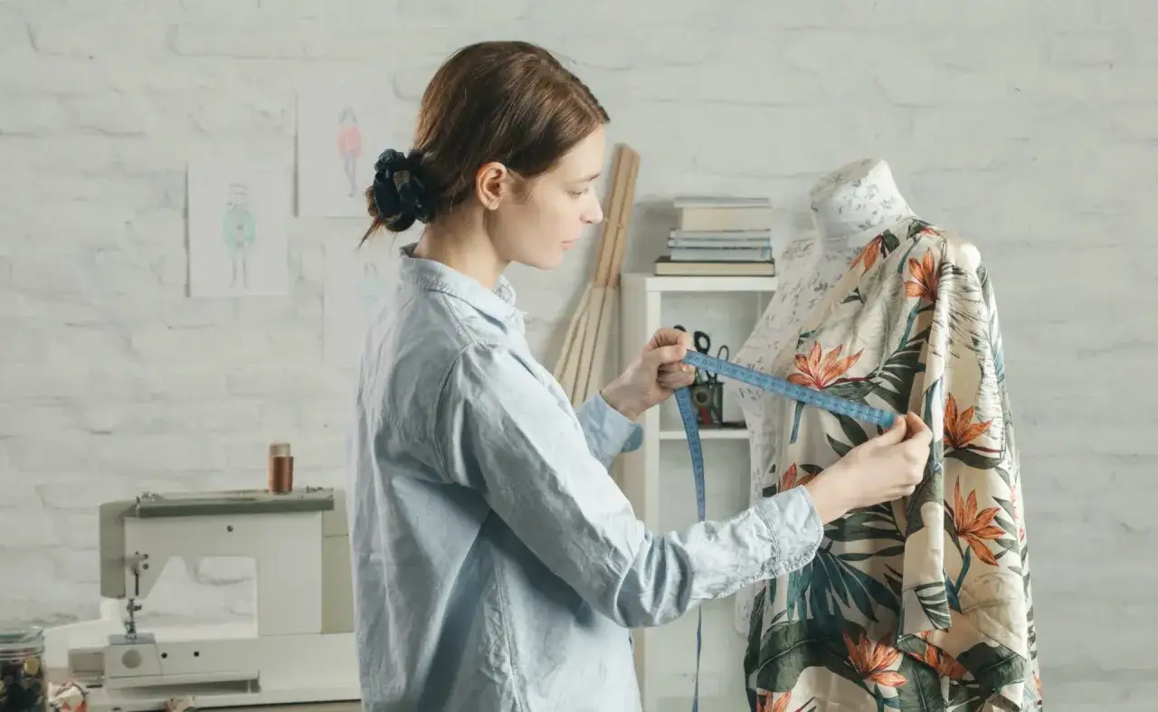 Diseñadora mide tela con estampado tropical para crear moda ecológica.