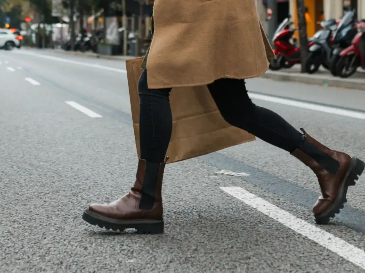 Mujer cruza la calle con botines Chelsea marrones y abrigo camel. &iexcl;As&iacute; se llevan los botines Chelsea mujer!