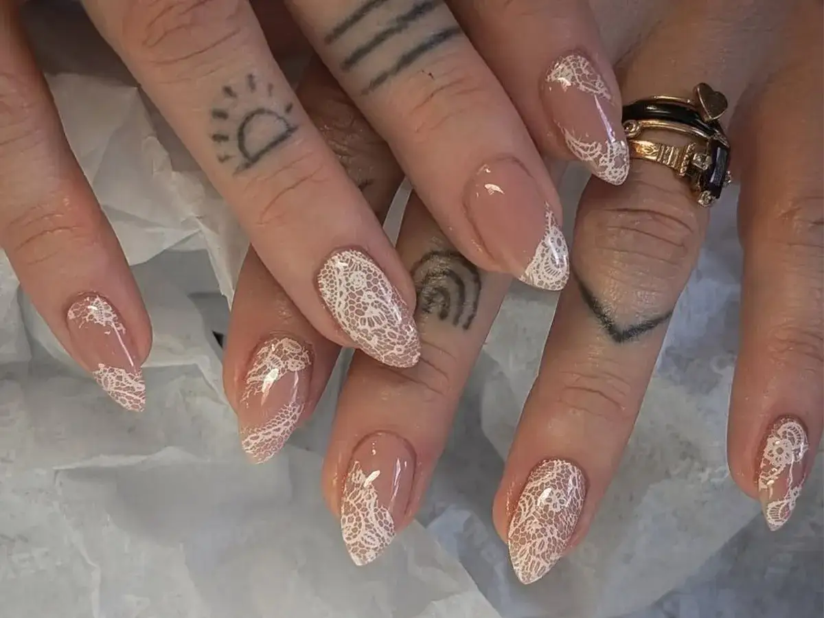 Manicura con delicado diseño de uñas bonitas en encaje blanco sobre base nude.