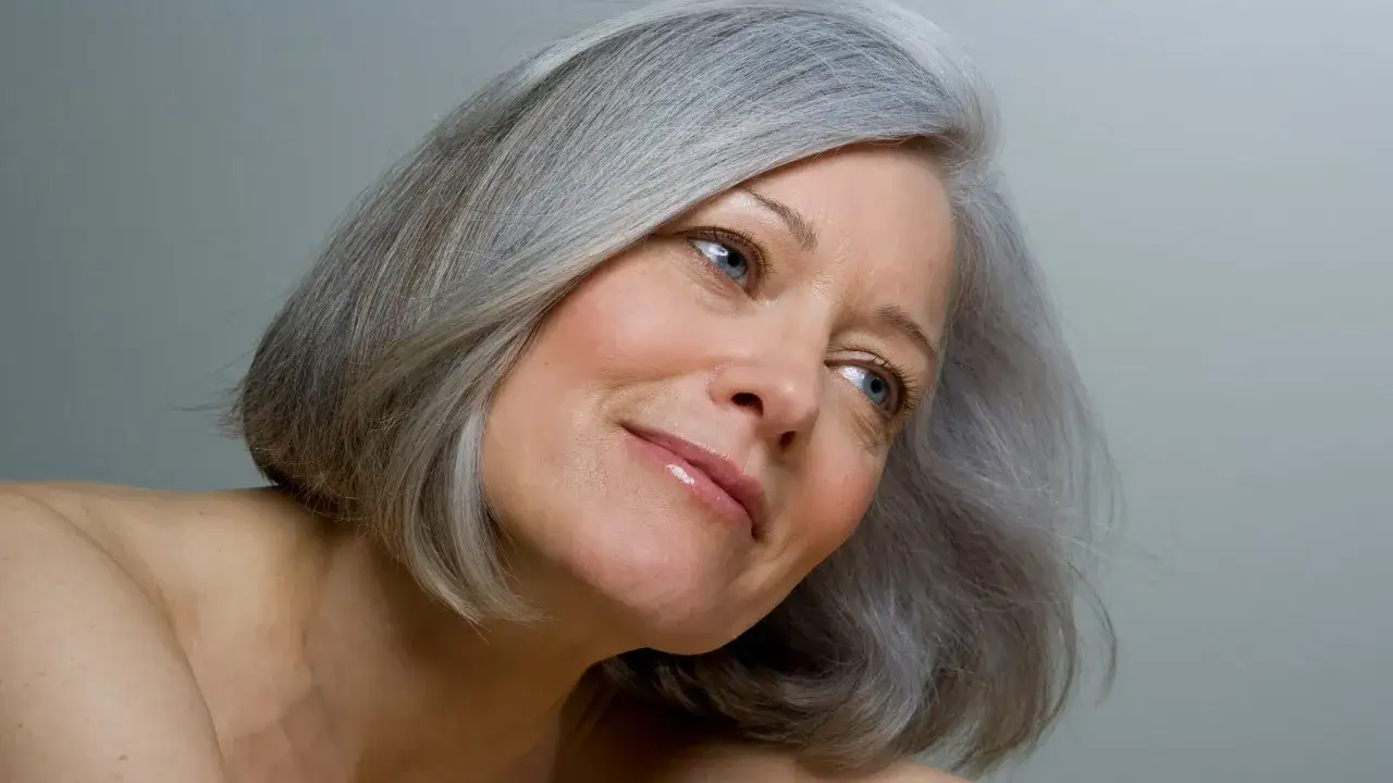 Mujer con cabello plateado, mostrando cómo cubrir canas sin tinte, con una mirada serena y natural.
