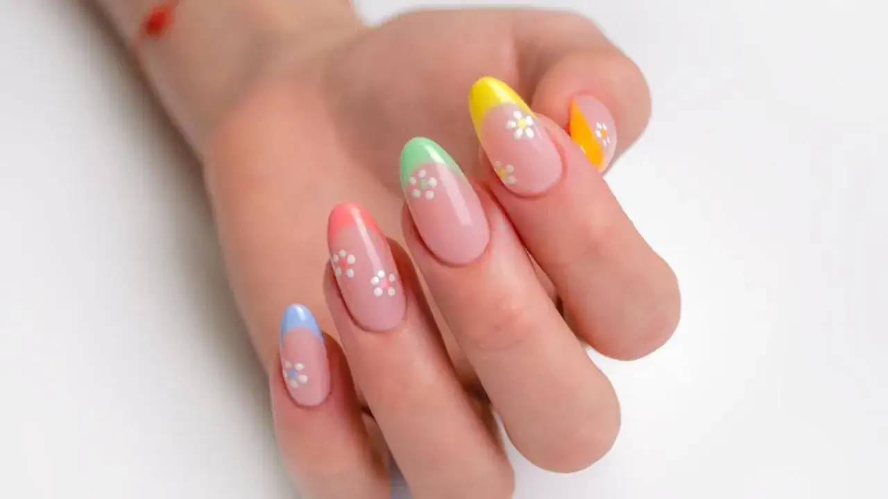 Manos con uñas francesas originales en tonos pastel y flores blancas.