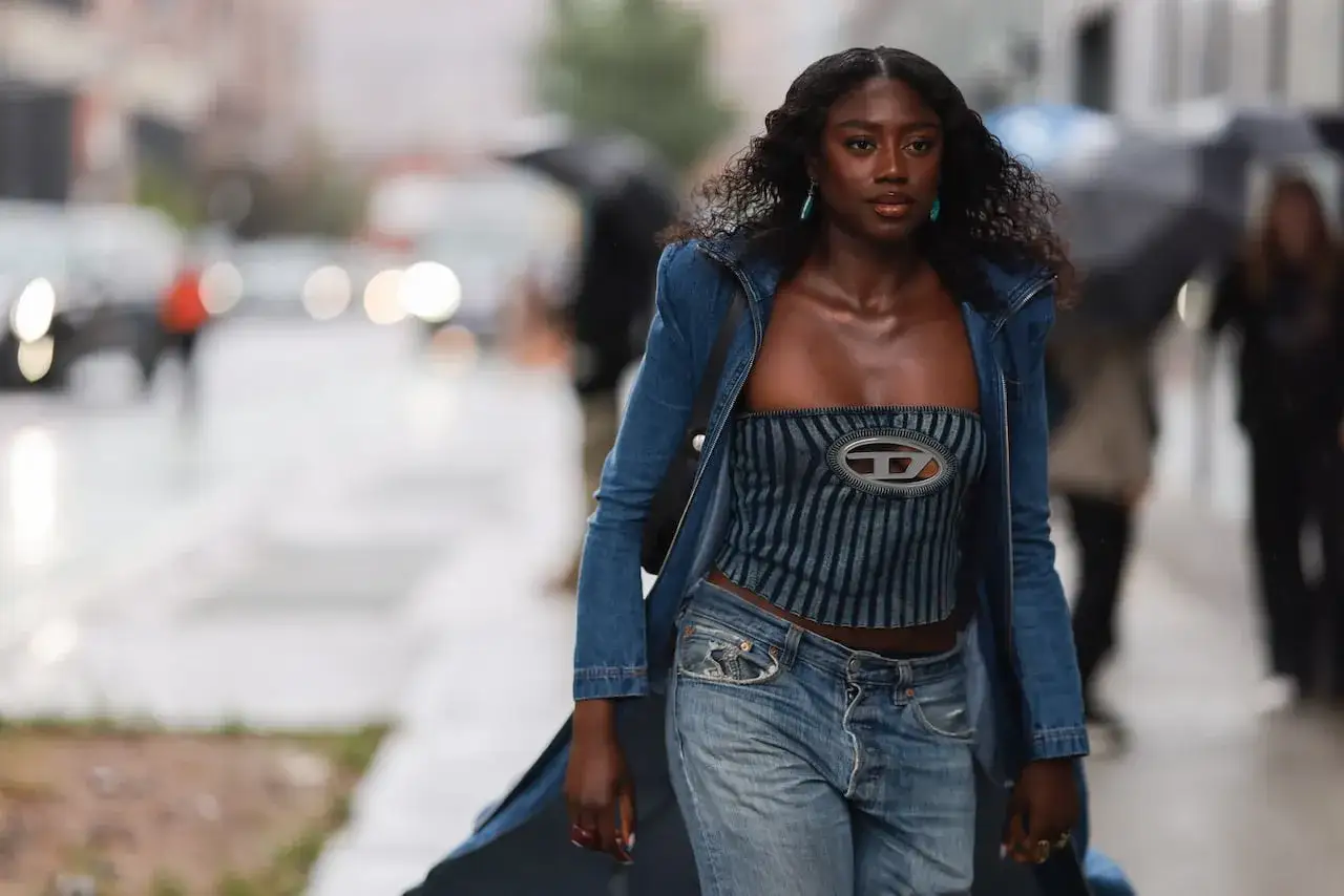 Mujer con estilo total denim on denim, luciendo un top de rayas y pantalones vaqueros de tiro bajo, con una chaqueta vaquera abierta.