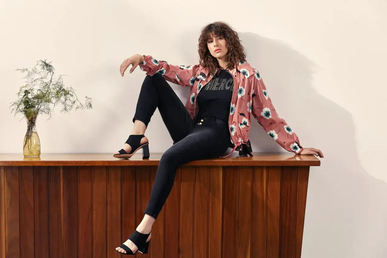 Chica con estilo moderno, luce un look casual chic con chaqueta estampada, jeans negros y sandalias.