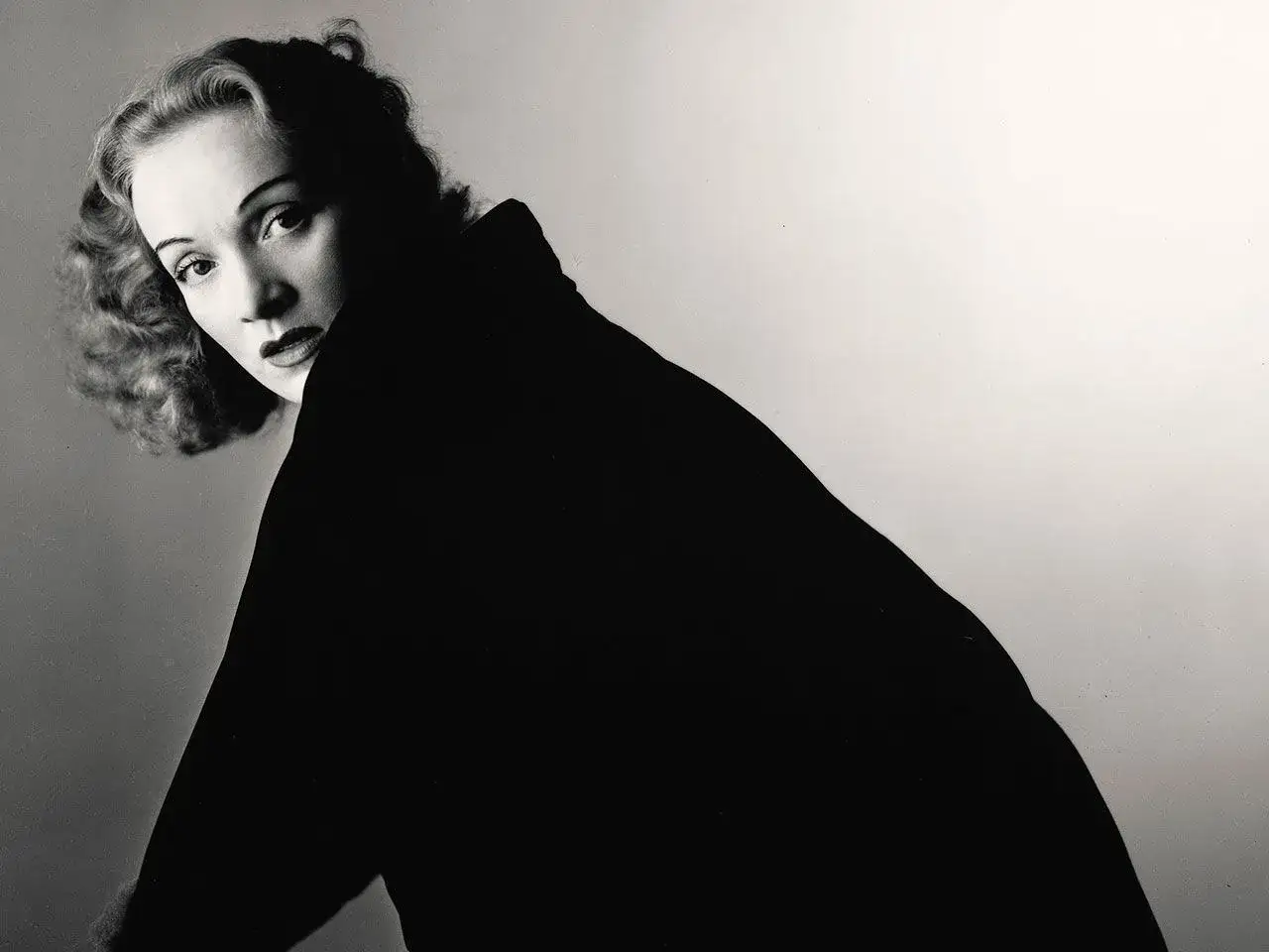 Retrato icónico de Marlene Dietrich, capturado por Irving Penn. Su mirada intensa y el cuello alto de su vestido negro crean un aura de misterio.