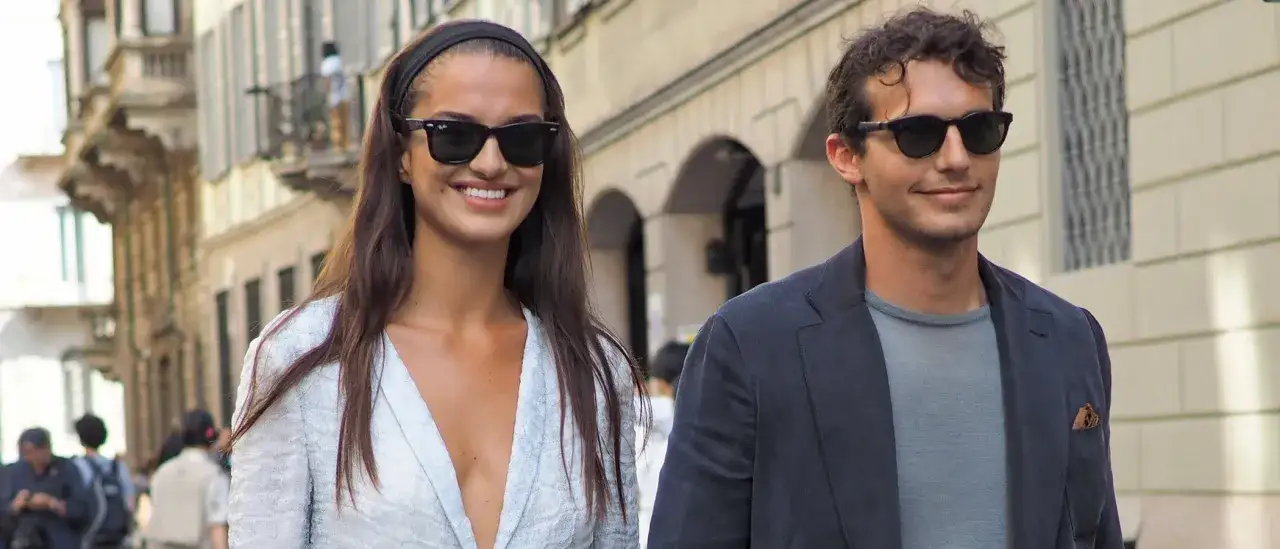 Pareja paseando con vestimenta smart casual. Ella lleva un vestido blanco y él un blazer azul marino.