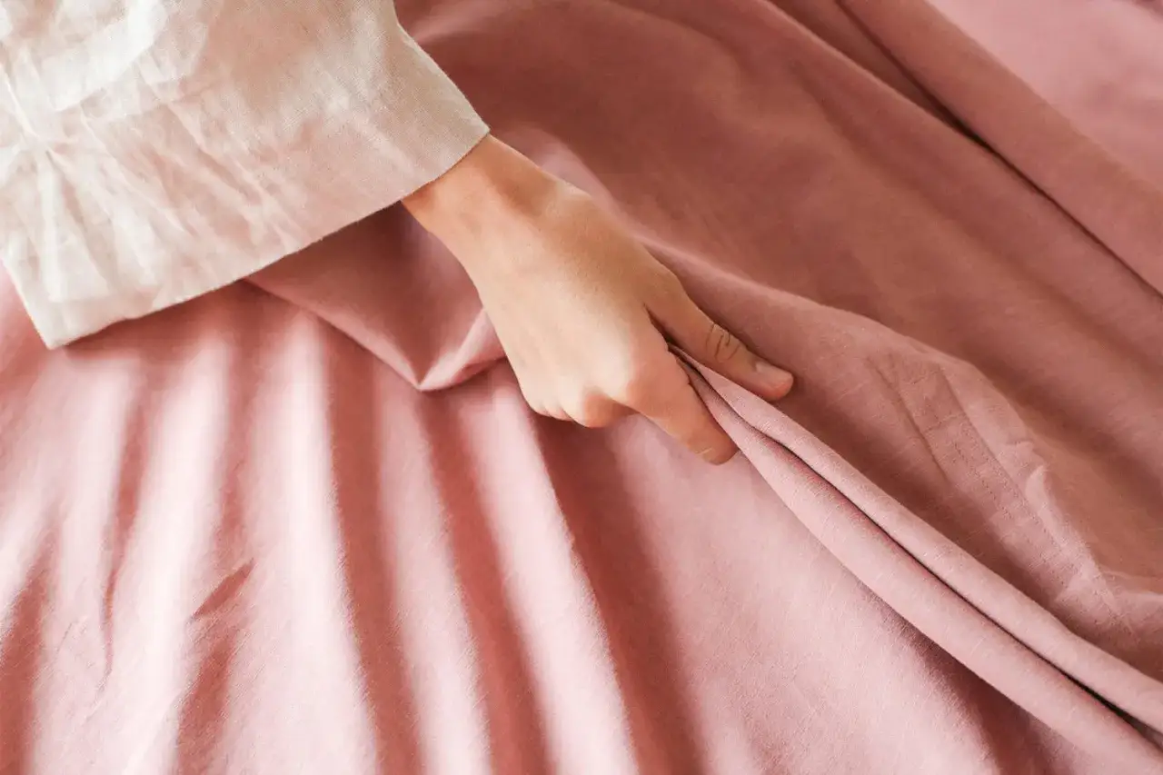 Mano tocando tela rosa, quiz&aacute;s para evaluar las desventajas del lyocell, como su tendencia a arrugarse.