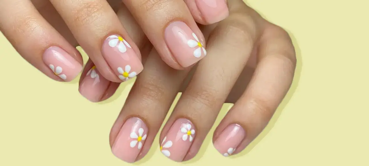 Manicura con diseño de margaritas blancas sobre base rosa pálido, perfecta para unas uñas verano llenas de frescura y alegría.
