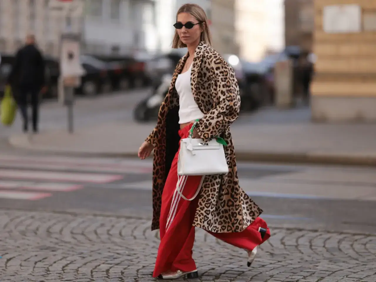 Mujer con estilo urbano: abrigo de leopardo, top blanco y pantalón de chándal rojo. ¡Una forma chic de como vestir con chandal mujer!
